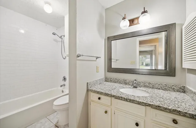 a bathroom with a granite countertop sink a toilet and shower