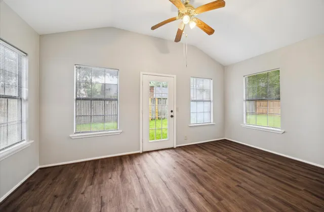 a view of an empty room with wooden floor and a window