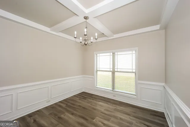 an empty room with wooden floor chandelier fan and windows