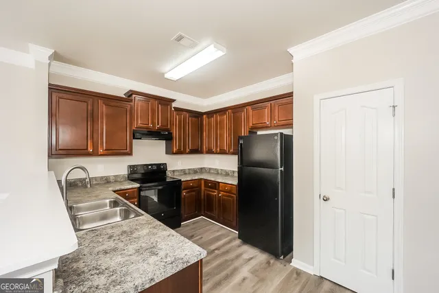 a kitchen with granite countertop stainless steel appliances a refrigerator a stove a sink a counter space and cabinets