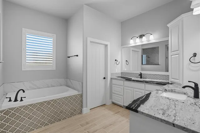 a bathroom with a tub sink and mirror