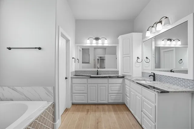 a bathroom with a granite countertop sink mirror and a bathtub