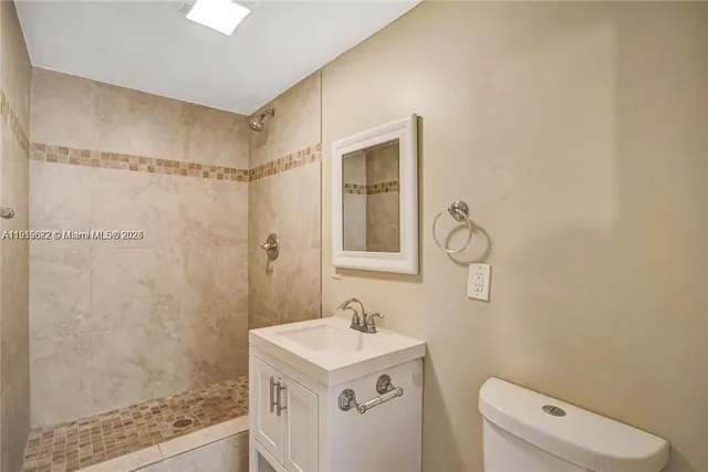 a bathroom with a granite countertop sink a toilet a shower and a mirror