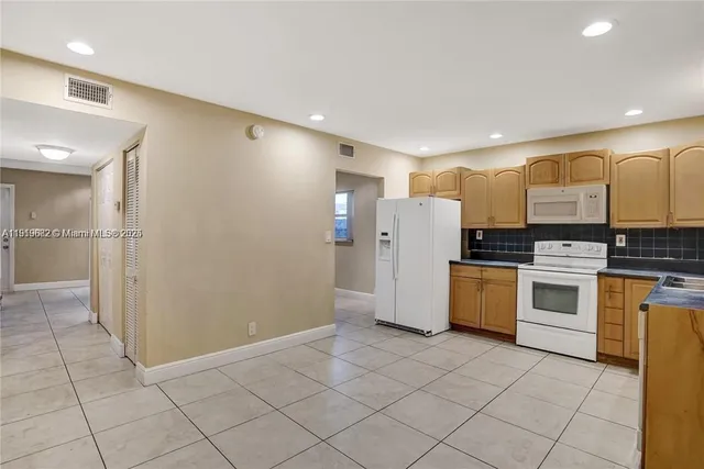 a kitchen with granite countertop a refrigerator and a stove top oven