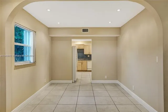 a view of an empty room with window and chandelier