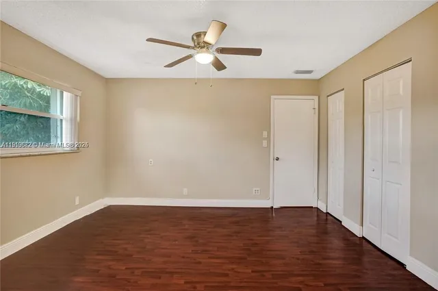 a view of empty room with wooden floor and fan