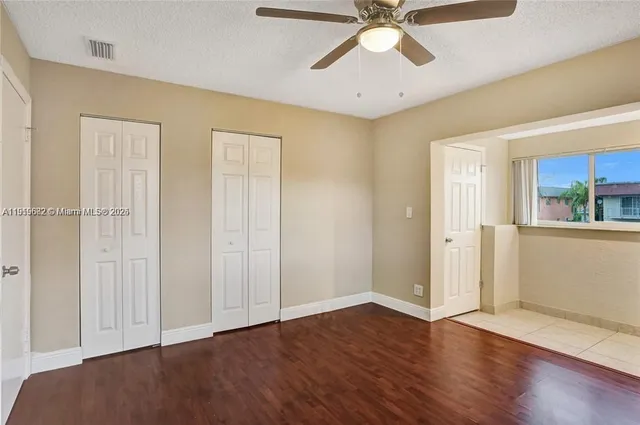 an empty room with wooden floor closet and windows