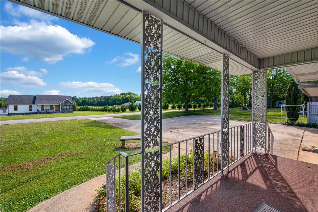 307 Calhoun Road Belton, SC 29627 - Photo 5 of 30 A welcoming front porch features decorative ironwork, overlooking a verdant lawn and a serene rural landscape.