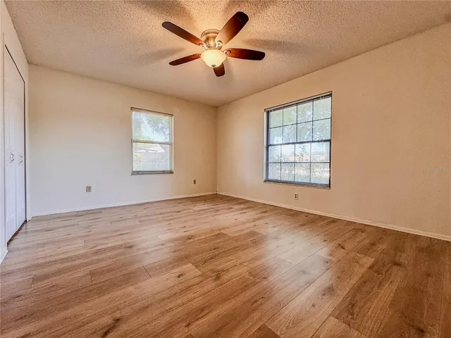 a view of empty room with wooden floor and fan