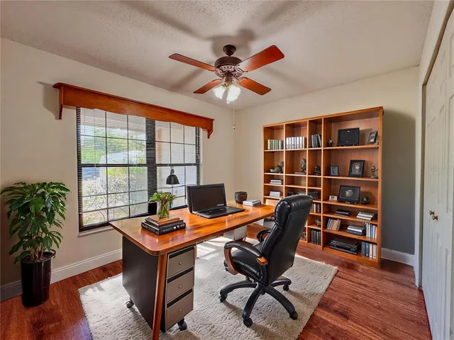 a view of empty room with wooden floor and fan