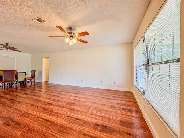 a view of a room with wooden floor and a ceiling fan
