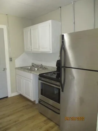 a kitchen with granite countertop a refrigerator and a stove top oven