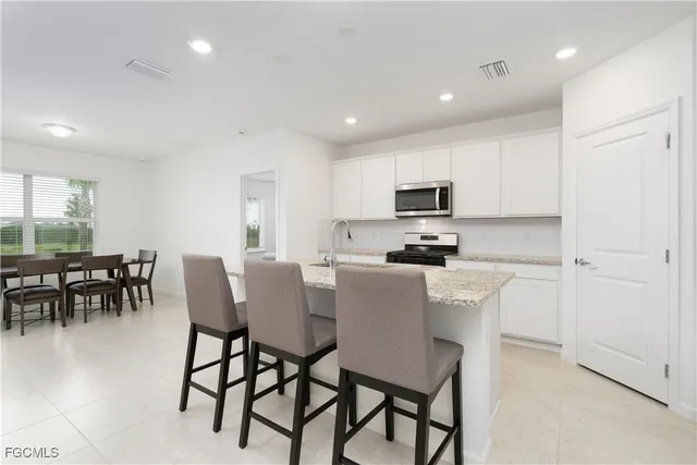 a kitchen with stainless steel appliances granite countertop a stove a refrigerator a microwave a dining table and chairs