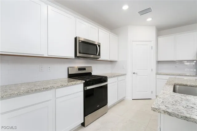 a kitchen with granite countertop white cabinets and stainless steel appliances