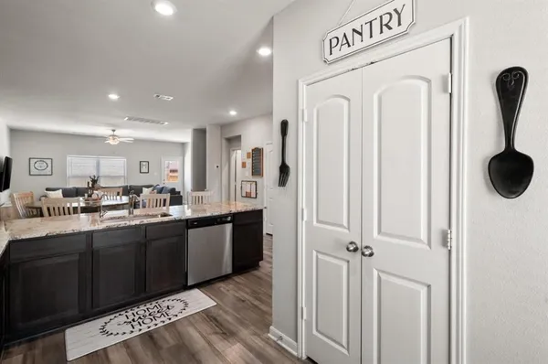 a hall with stainless steel appliances granite countertop a refrigerator and a sink