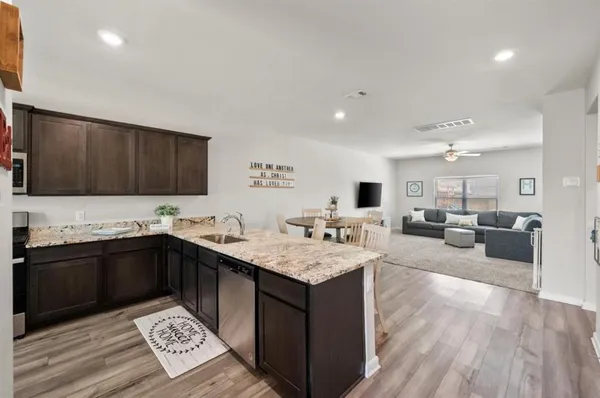 a kitchen with granite countertop a sink dishwasher stove and cabinets