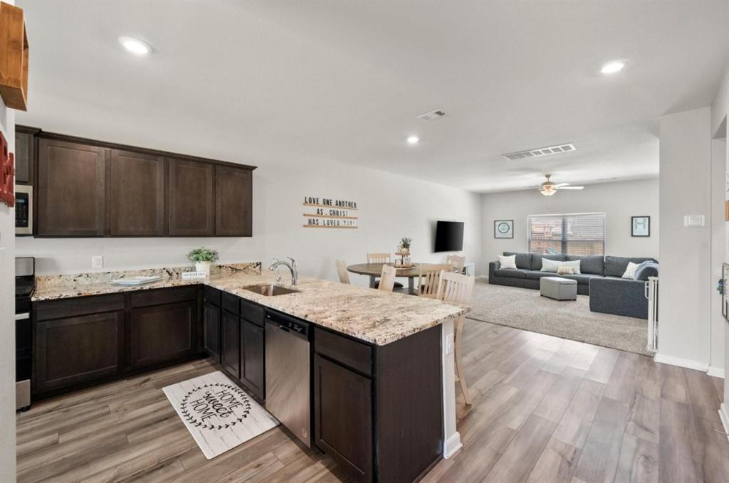 159 Sammy Fowler Avenue Venus, TX 76084 - Photo 10 of 36 a kitchen with granite countertop a sink dishwasher stove and cabinets