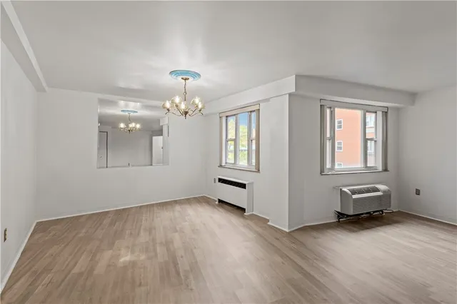 a view of an empty room with window and wooden floor