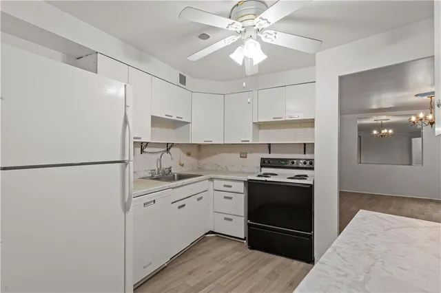 a kitchen with stainless steel appliances granite countertop a refrigerator a sink a stove and white cabinets