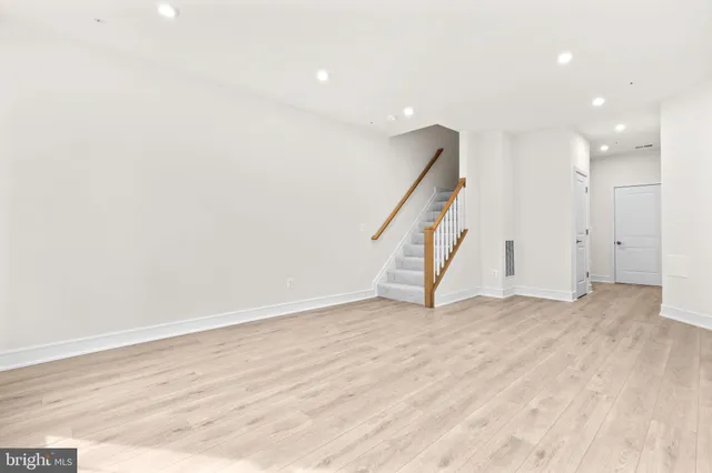 a view of an empty room with wooden floor and stairs
