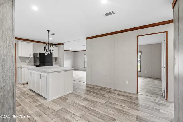 a kitchen with white cabinets and wooden floor