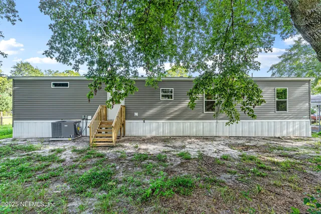 a view of a house with a yard and a large tree