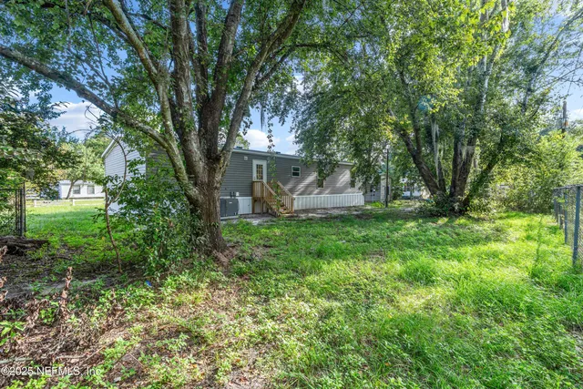a view of a house with backyard and a tree