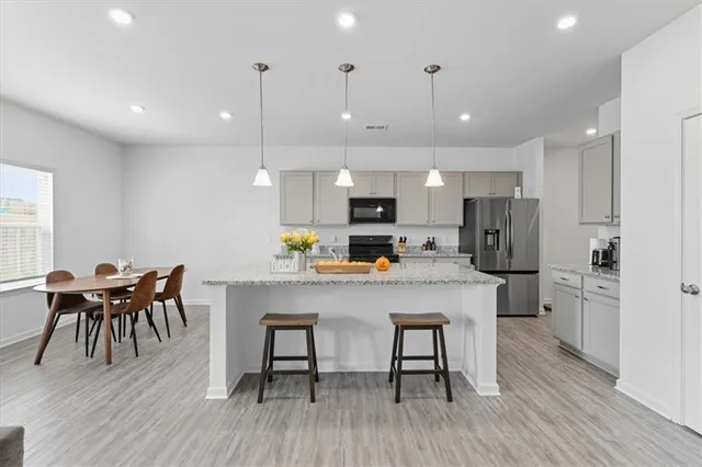 a kitchen with stainless steel appliances a dining table chairs stove refrigerator and cabinets