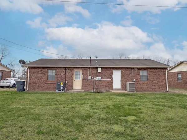 a view of a brick house with a big yard and large tree