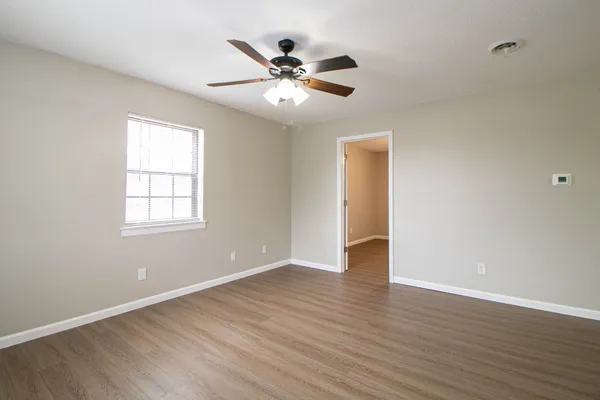 an empty room with wooden floor and windows