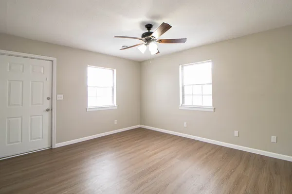 a view of an empty room with wooden floor and a window