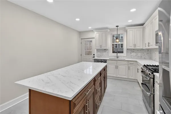a kitchen with a sink a stove a refrigerator and white cabinets