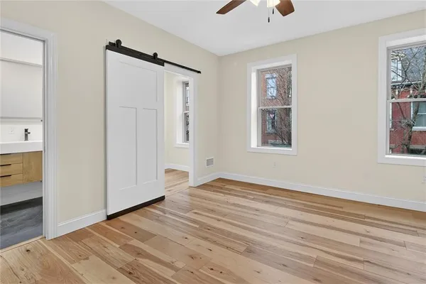 a view of an empty room with window and wooden floor