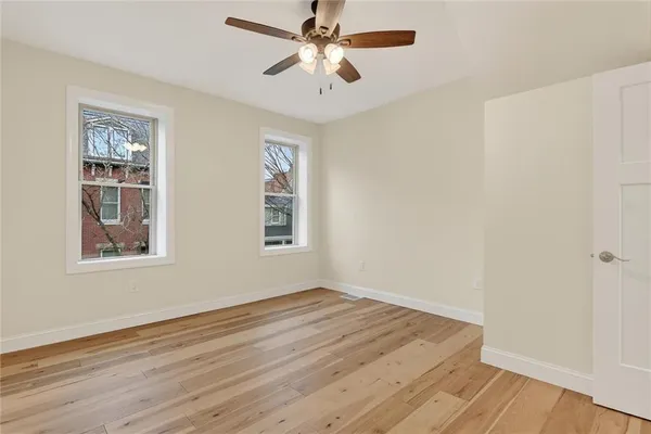 a view of empty room with wooden floor and fan