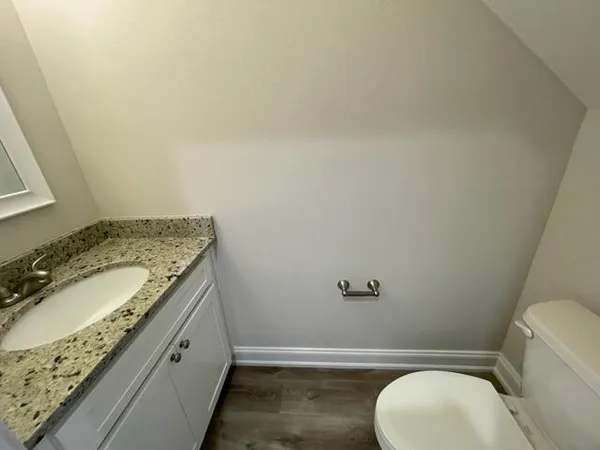 a bathroom with a granite countertop toilet sink and mirror