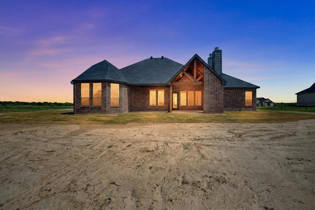 517 Longhorn Lane Springtown, TX 76082 - Photo 37 of 39 View of front facade with a chimney, a patio area, brick siding, and a yard