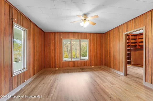 a view of an empty room with a window and wooden floor
