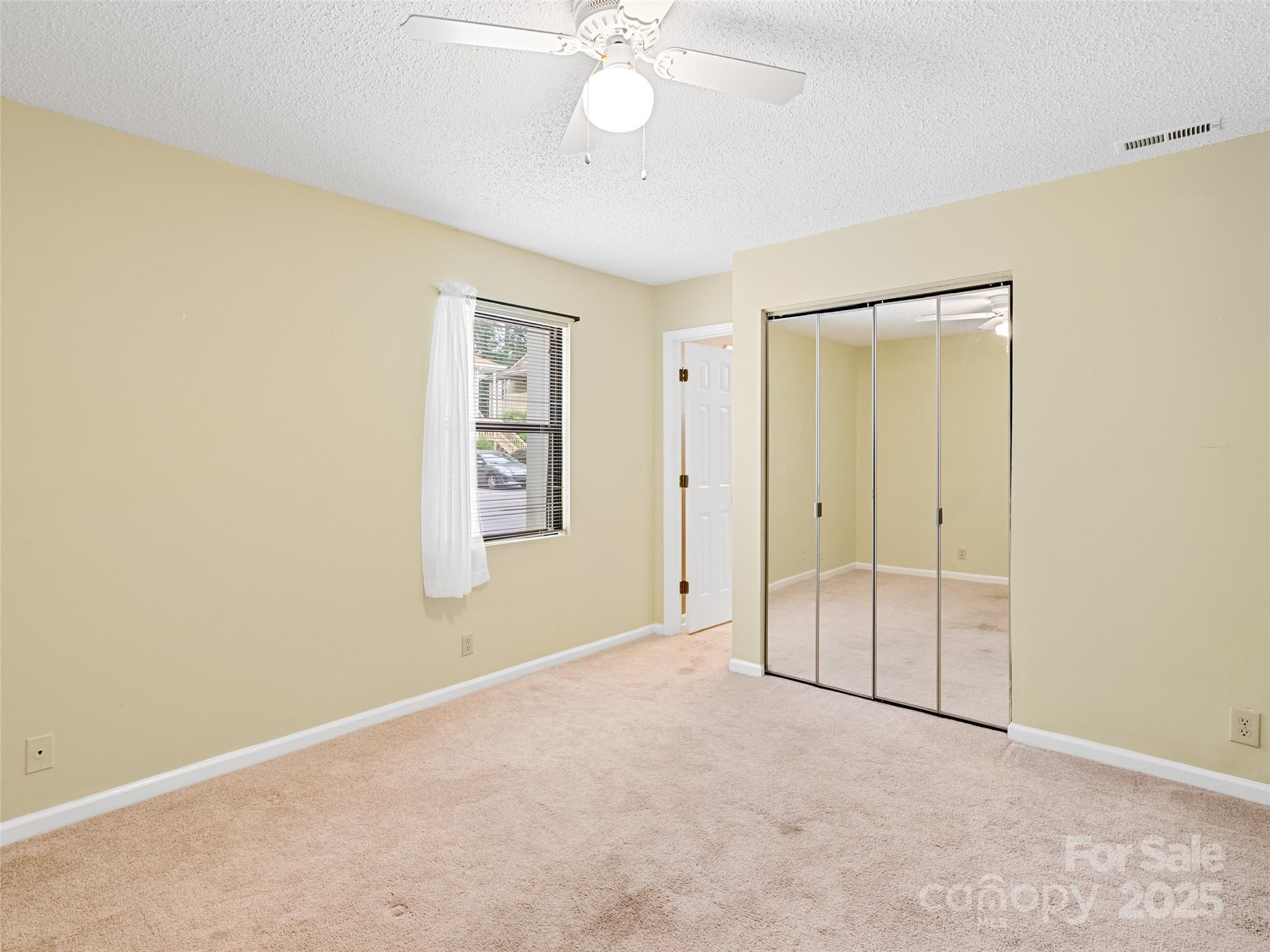 110 Heywood Road, Unit 17C Arden, NC 28704 - Photo 11 of 26 an empty room with a ceiling fan and window
