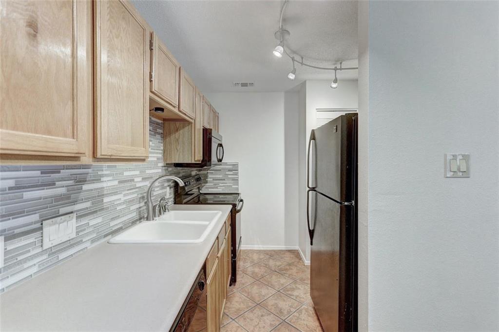 3115 Helms Street, Unit 204 Austin, TX 78705 - Photo 3 of 13 Functional kitchen with ample cabinetry and a tiled backsplash, offering everyday convenience.