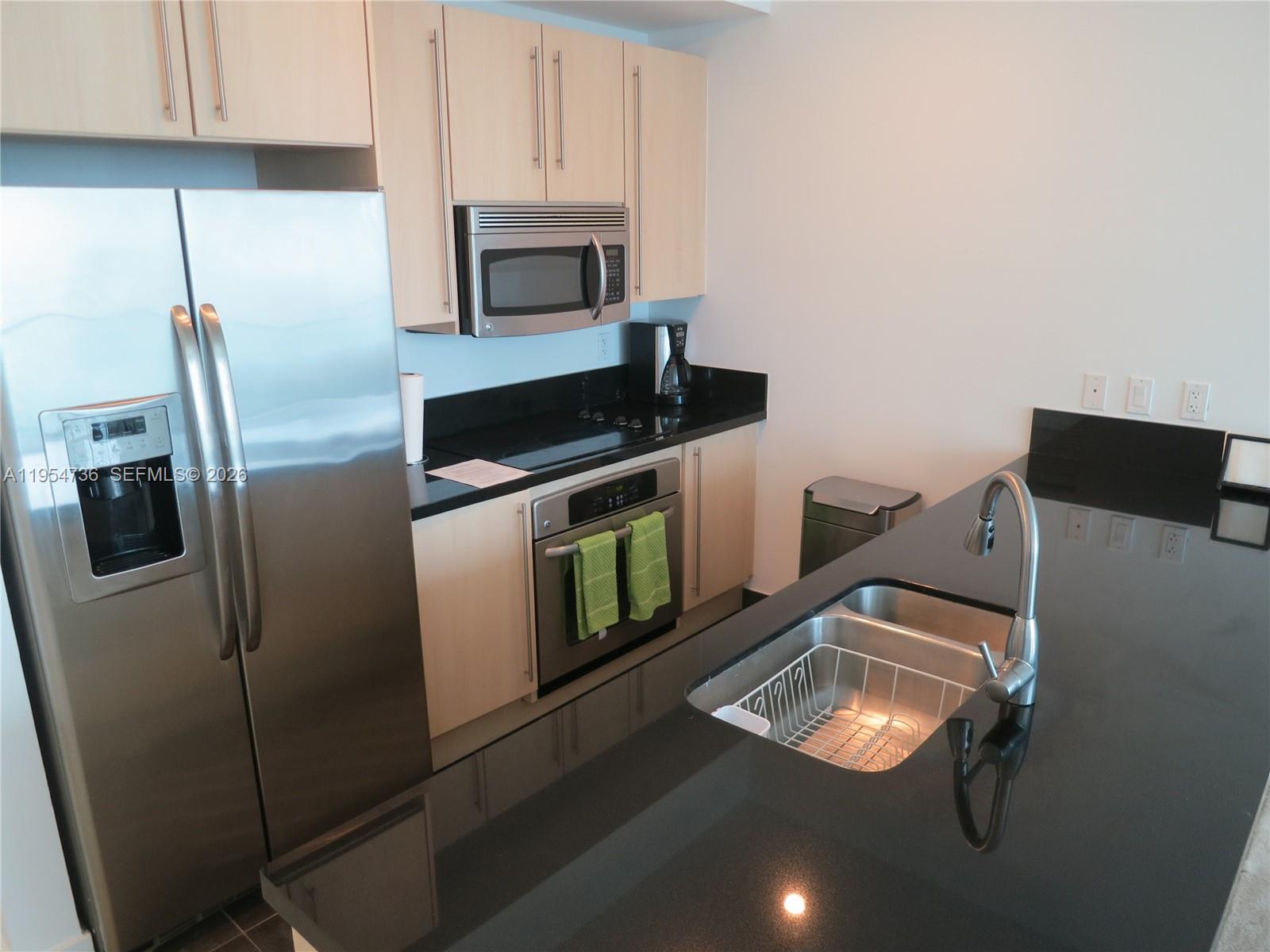 1111 Southwest 1st Avenue, Unit 3022N Miami, FL 33130 - Photo 4 of 14 a kitchen with stainless steel appliances a stove a refrigerator a sink and a microwave