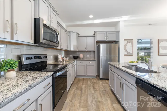 a kitchen with stainless steel appliances granite countertop a sink stove microwave and refrigerator