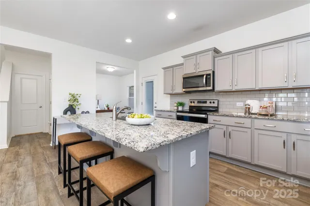 a kitchen with a stove a sink a microwave a dining table and chairs