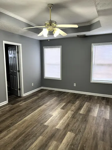 an empty room with wooden floor chandelier and windows