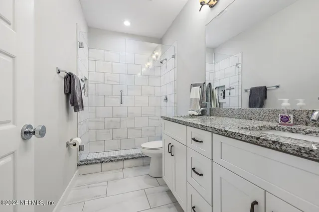 a bathroom with a granite countertop sink a toilet and shower