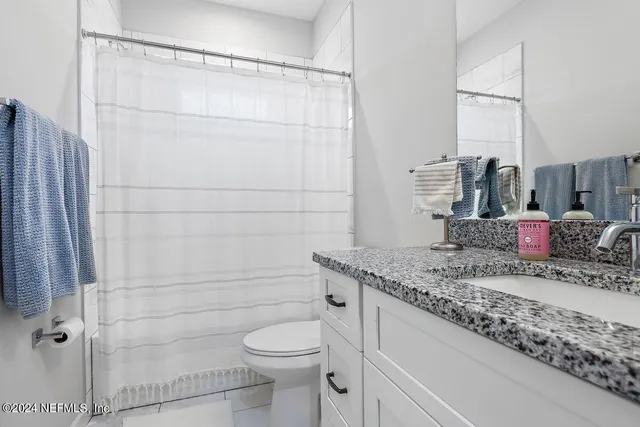 a bathroom with a granite countertop sink a toilet and shower
