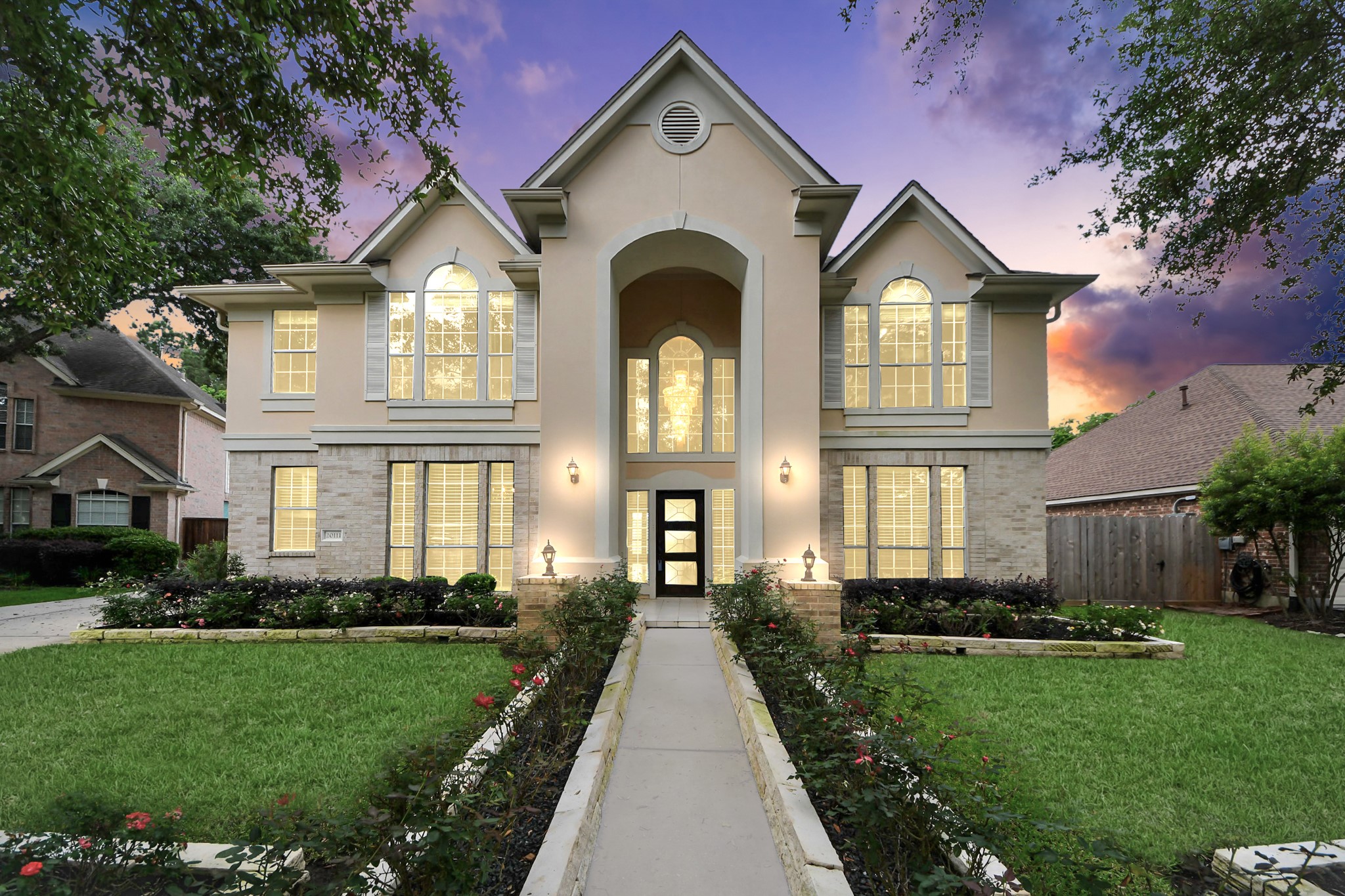 This stunning two-story home features elegant architecture with large, arched windows and a welcoming entrance. The well-maintained front yard is beautifully landscaped with a walkway leading to the front door. Ideal for family living in a picturesque neighborhood.