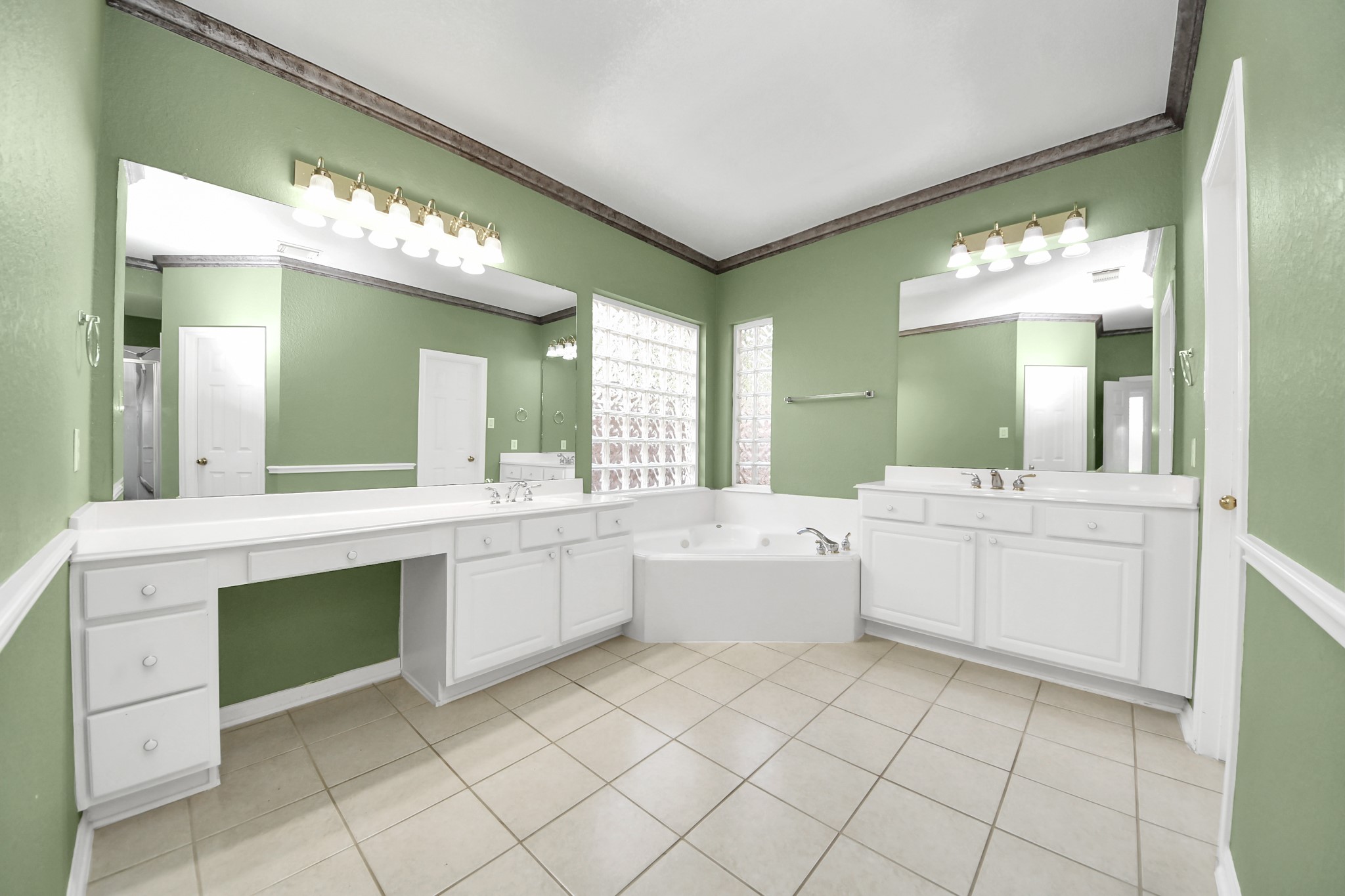 20111 Biscayne Hill Court Spring, TX 77379 - Photo 22 of 44 This bathroom features green walls, dual vanities with large mirrors, a central soaking tub, and ample lighting, creating a bright and spacious atmosphere.