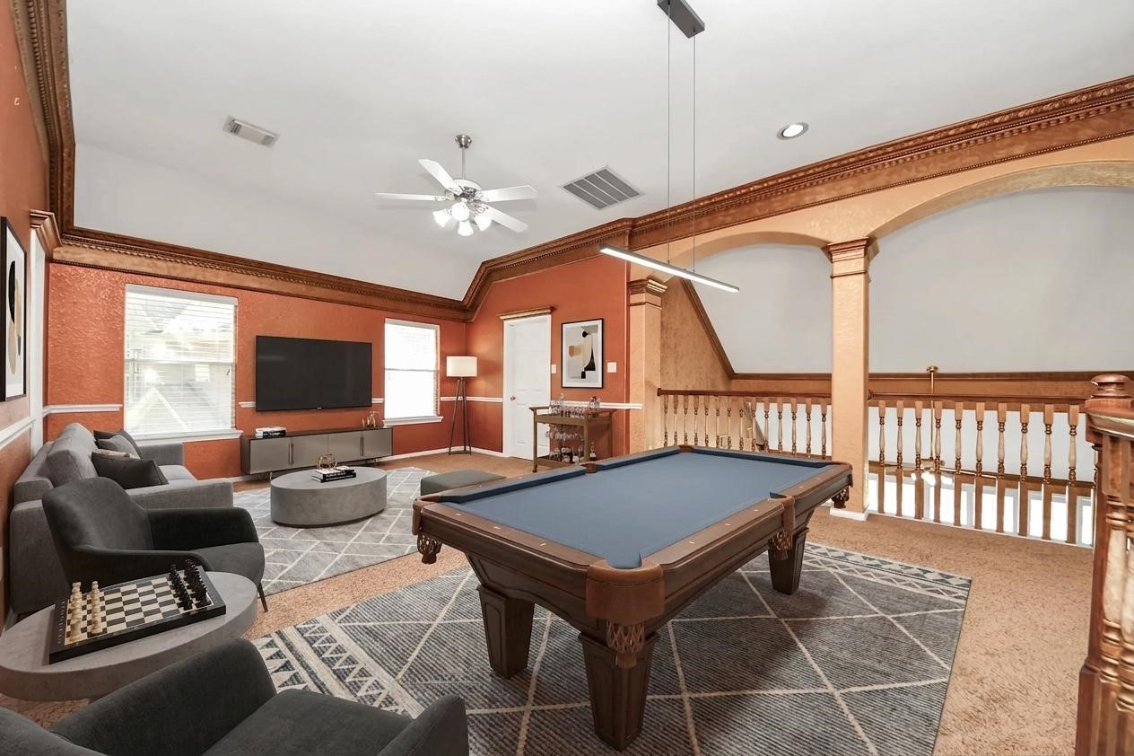 20111 Biscayne Hill Court Spring, TX 77379 - Photo 28 of 44 This inviting game room features a pool table, comfortable seating, and a large TV. The space is accented by warm wall colors, elegant crown molding, and ample natural light from two windows. Perfect for entertainment and relaxation.