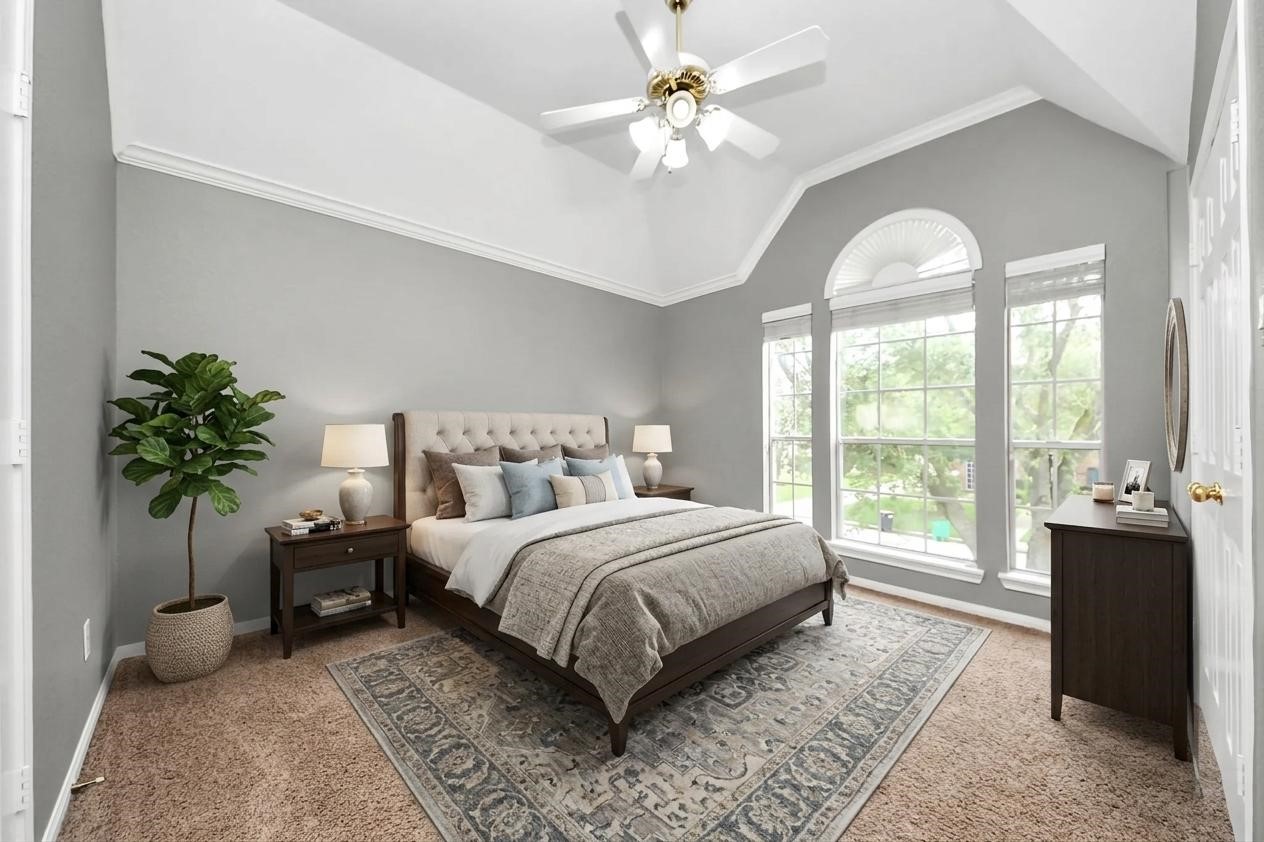 20111 Biscayne Hill Court Spring, TX 77379 - Photo 29 of 44 This bedroom features a high vaulted ceiling with a ceiling fan, large arched windows providing ample natural light, and a cozy, neutral color scheme. The room is furnished with a plush bed, nightstands, and a dresser, complemented by a stylish area rug and indoor plant.