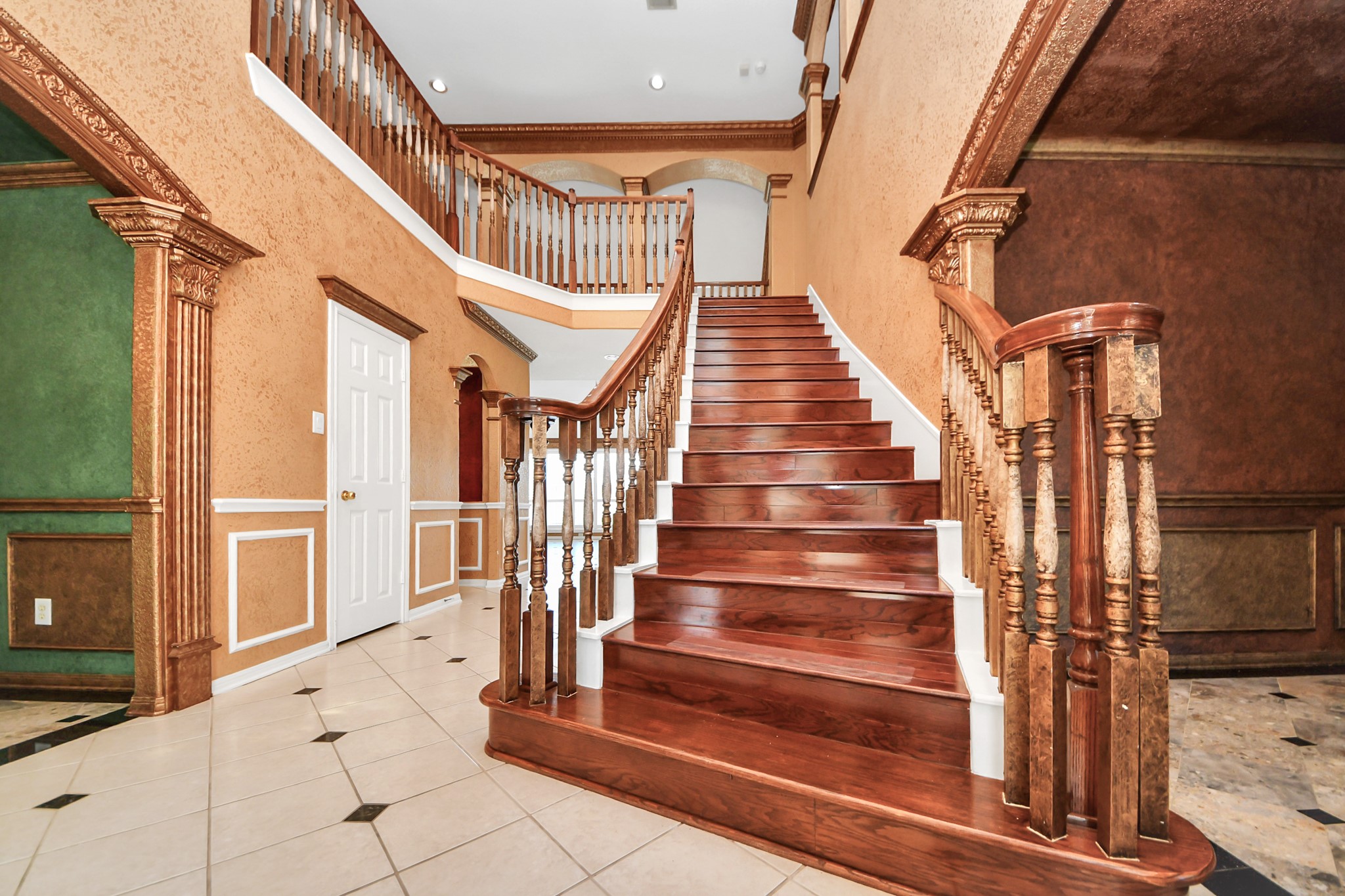 20111 Biscayne Hill Court Spring, TX 77379 - Photo 5 of 44 This elegant foyer features a grand wooden staircase with ornate railings, high ceilings, and rich, warm wall and floor tones, offering a luxurious and inviting entrance to the home.